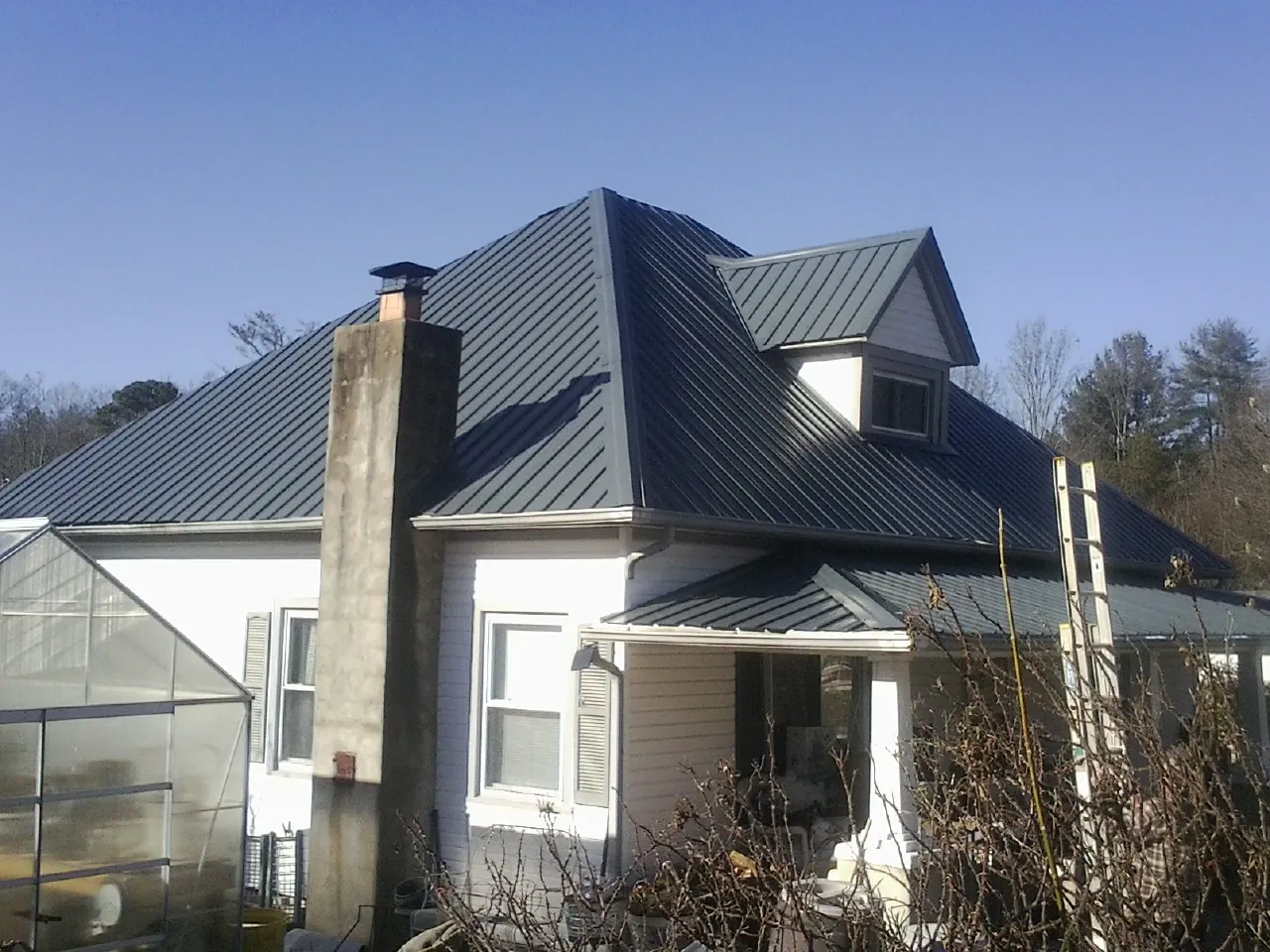 Dark blue standing seam metal roof on a white farmhouse with dormer — Slate & Tile Roof Repair by Roofing Brothers in Pickerington