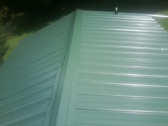 New green metal panels meeting at the ridge of a roof — Flat Roof Repair work by our crew in Pickerington