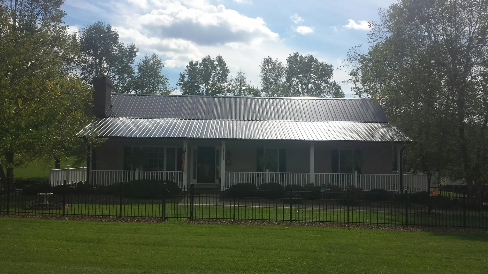 Gray metal roof on a brick ranch with a full width front porch — Gutter Guard Installation work by our crew in Pickerington