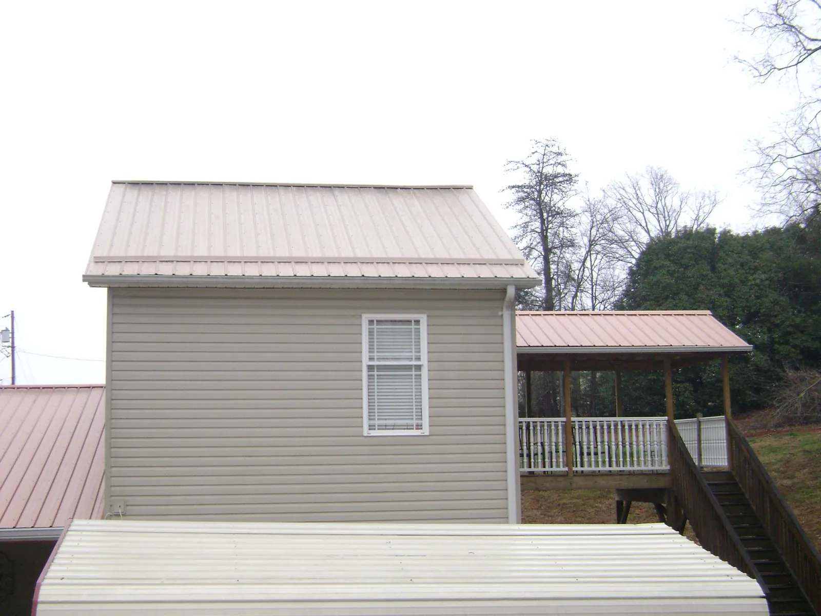 Tan metal roofs on a two story addition and attached porch, from a Roof Replacement job in Pickerington