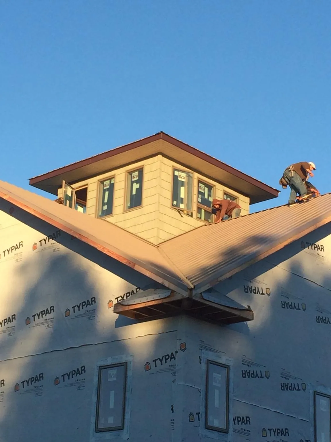 Roofers working around a rooftop cupola on a new metal roof at sunset — Roof Waterproofing in Pickerington by Roofing Brothers